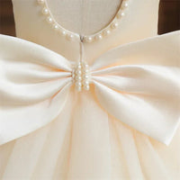 cream elegant V-back dress for girls with pearl neckline and large satin bow detail