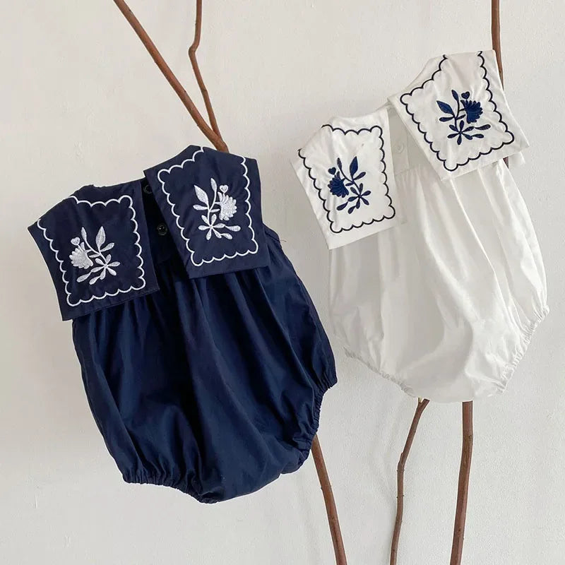 Navy and white embroidered baby romper with sailor collar for infants with floral embroidery detail