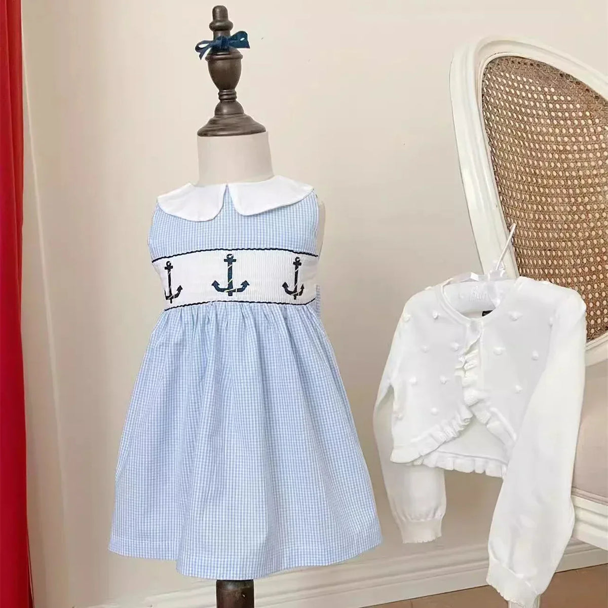 Blue and white embroidered girls party dress with anchor design on toddler mannequin and white cardigan