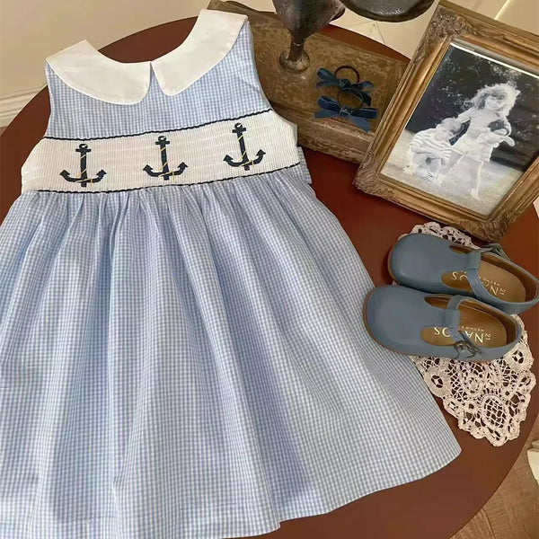 Blue and white embroidered girls party dress with anchor design for toddler girls on table