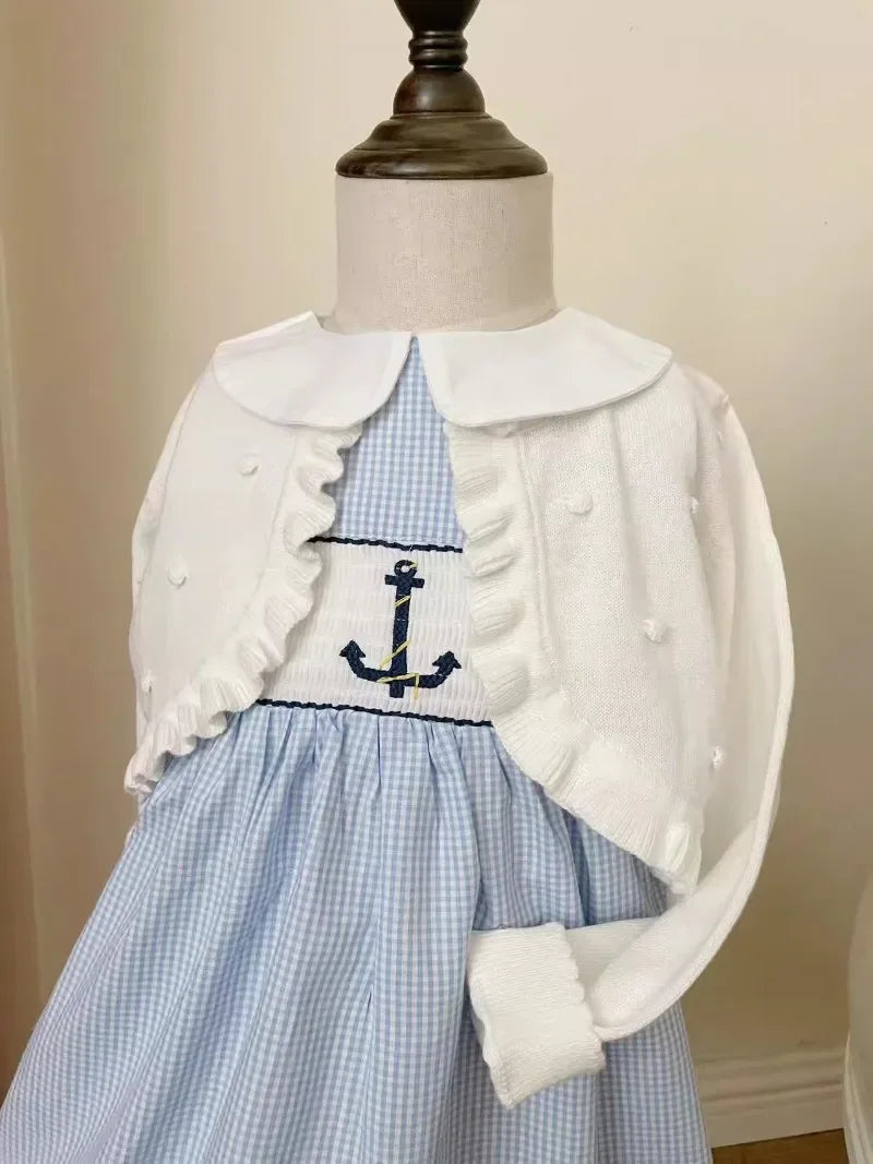 blue and white embroidered girls party dress with anchor design and white knit sweater on mannequin