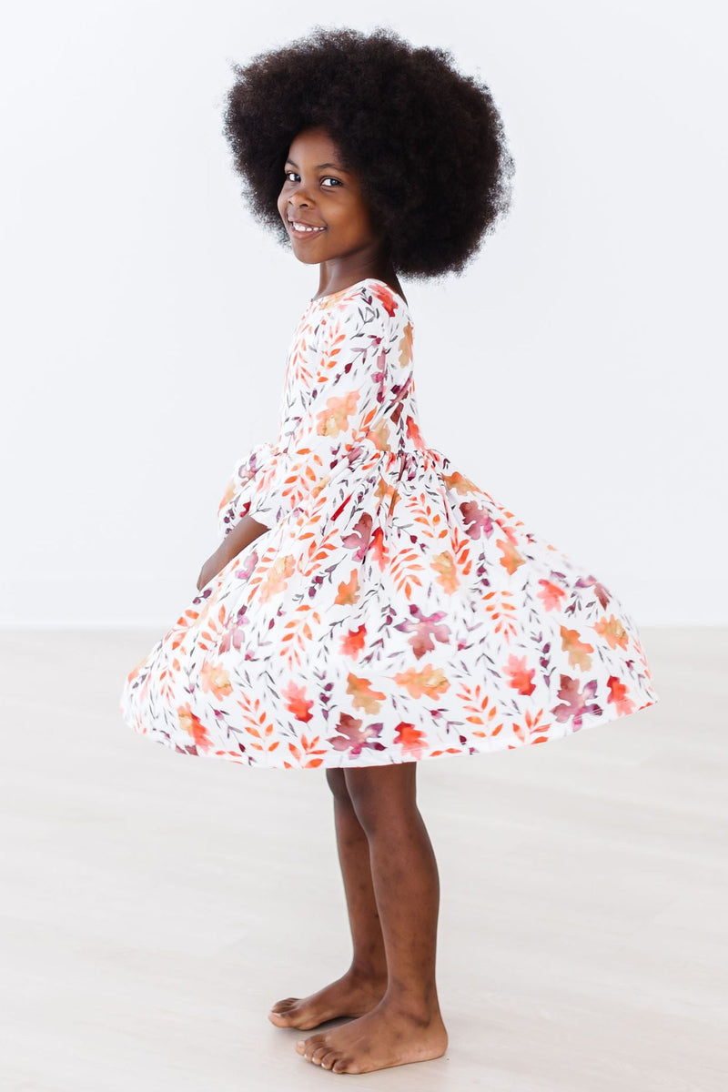 Side view of a cheerful girl spinning in the Falling Leaves 3/4 Sleeve Pocket Twirl Dress by Mila & Rose, highlighting the dress’s puffy skirt and playful style.