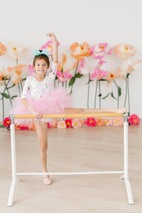 young girl wearing pink fairy princess tutu leotard for girls with teal bow doing ballet stretch at barre