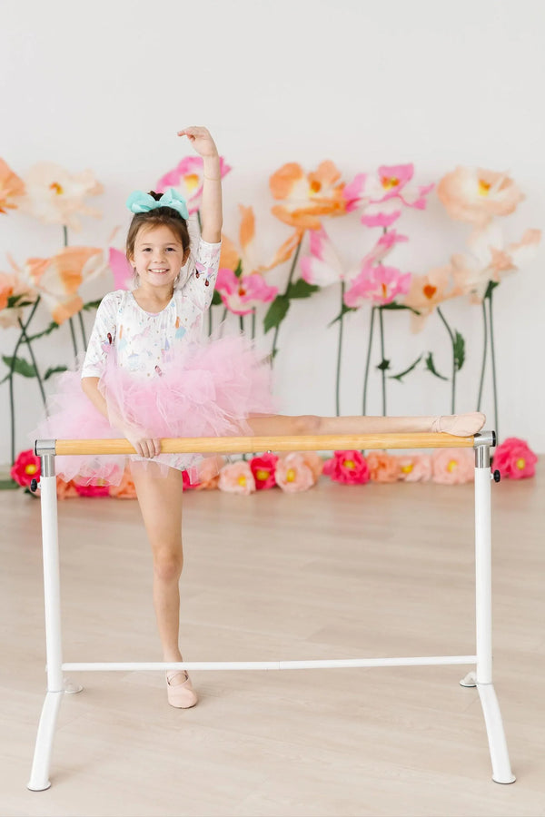 young girl wearing pink fairy princess tutu leotard for girls with teal bow doing ballet stretch at barre