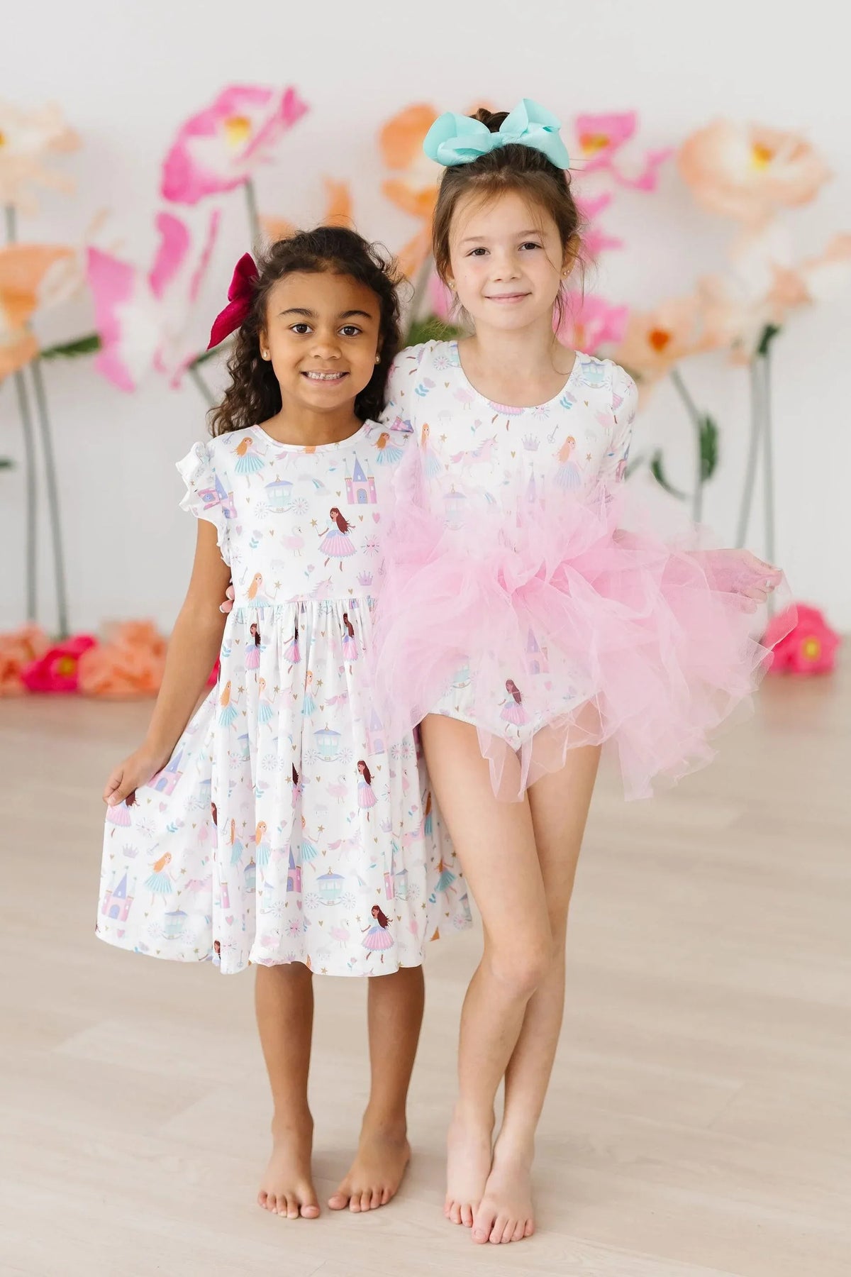Girl wearing white fairy princess tutu leotard for girls with pink tutu and blue bow posing with friend