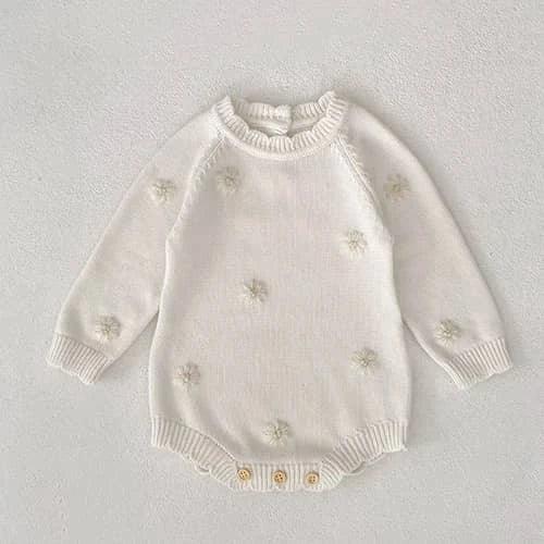 cream-colored fall knit baby romper with flower details for infants laid flat