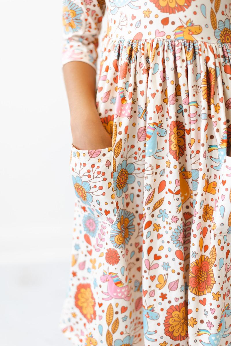 Close-up of the Retro Unicorns 3/4 Sleeve Pocket Twirl Dress for girls, featuring a colorful floral design and handy pockets, perfect for twirling and play.