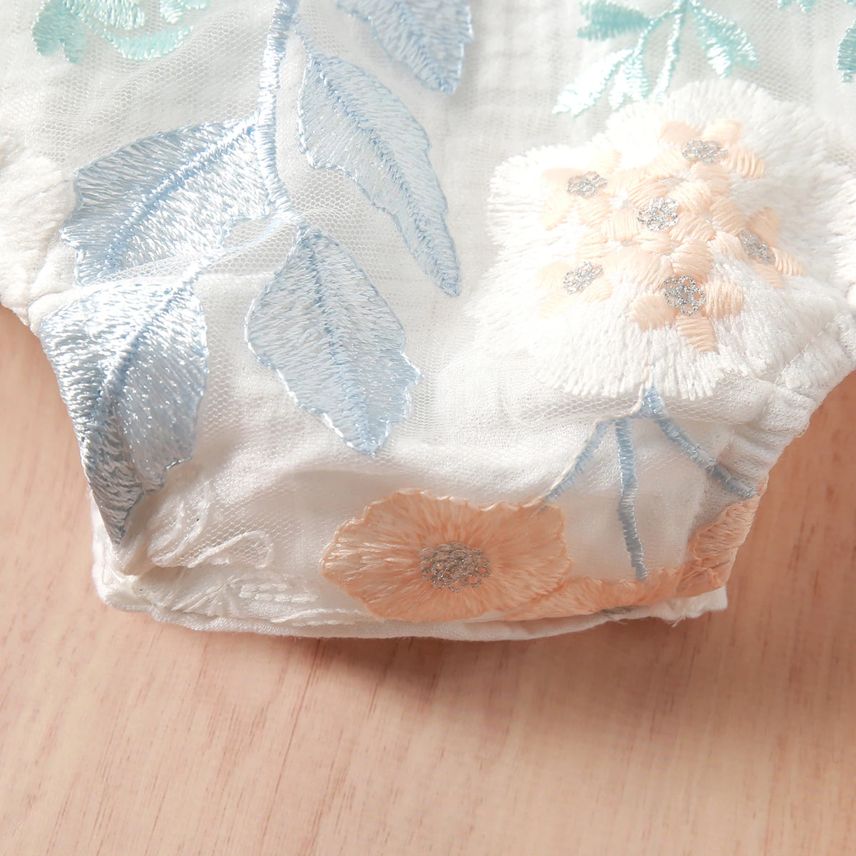 white floral baby romper for babies with blue green and peach flower embroidery delicate design