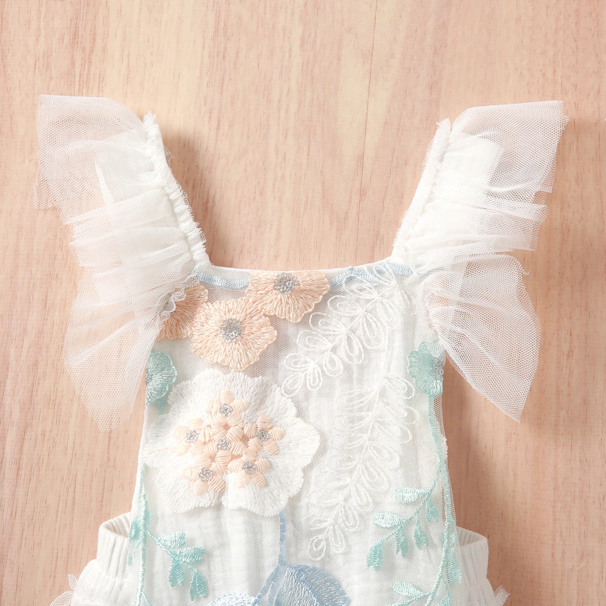 Floral baby romper in white with pastel embroidered flowers and ruffled tulle sleeves for infants