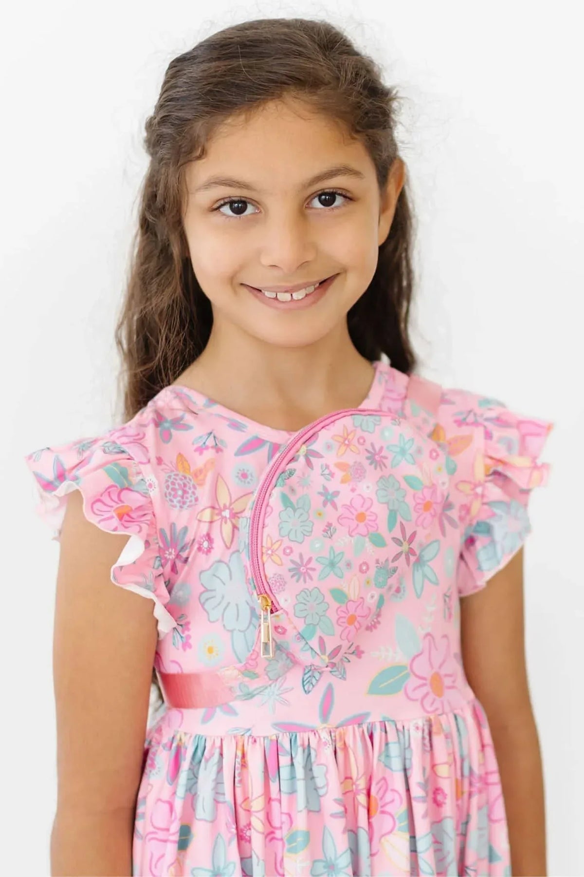 young girl wearing pink floral flutter sleeve twirl dress for girls smiling and standing