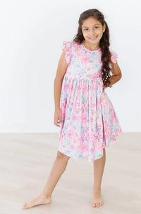 Young girl wearing pink floral flutter sleeve twirl dress for girls smiling and posing barefoot