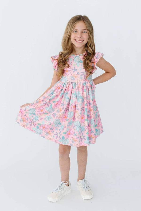 Young girl wearing a pink floral flutter sleeve twirl dress for girls smiling and holding the skirt