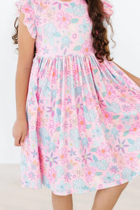 Young girl wearing a pink floral flutter sleeve twirl dress for girls holding the skirt out