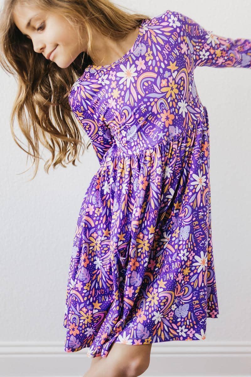 Young girl wearing purple floral girls 3/4 sleeve twirl dress spinning indoors