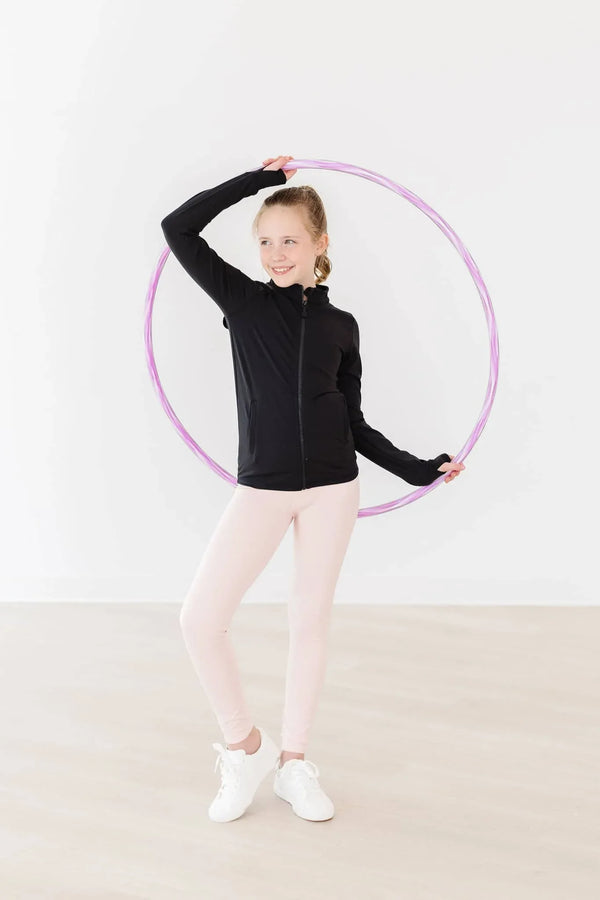 Young girl wearing pink girls active leggings and black jacket posing with a purple hula hoop