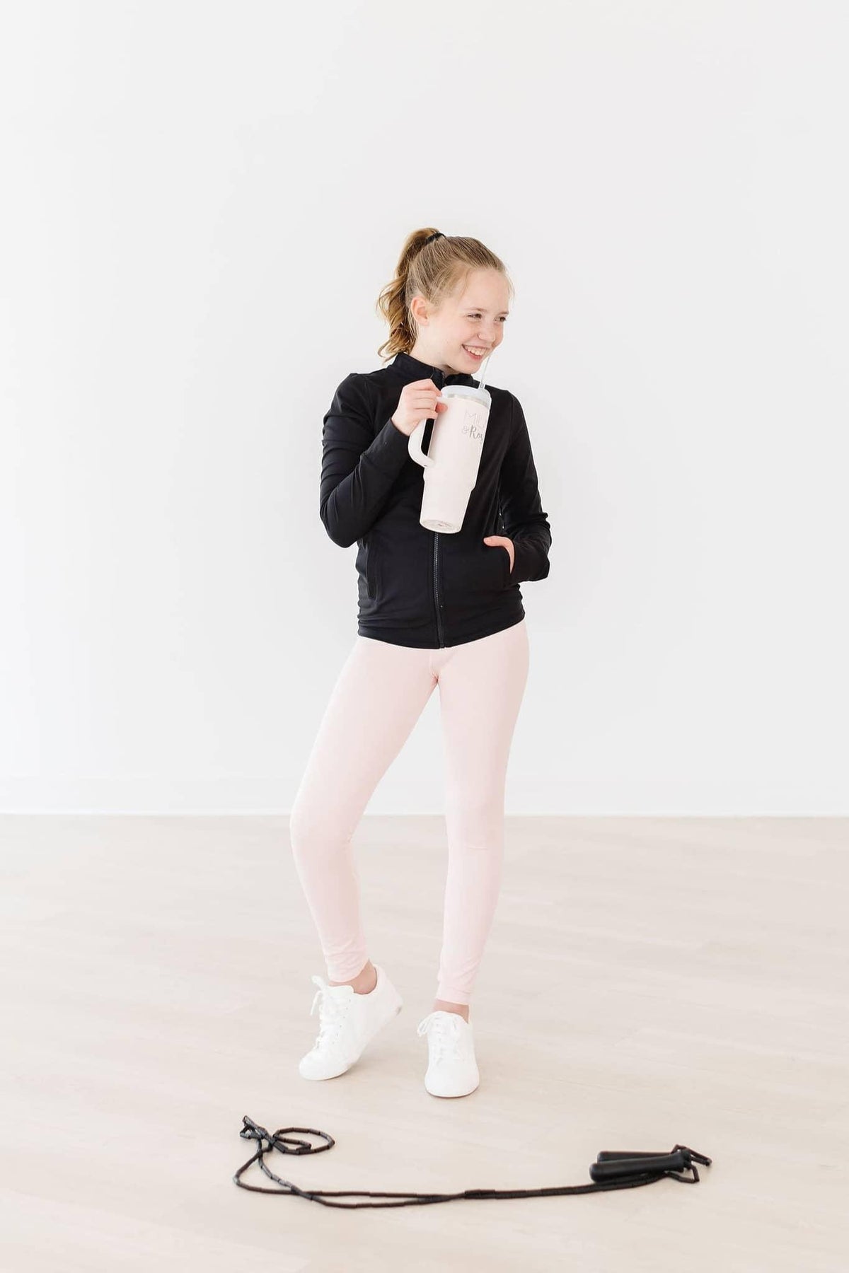 young girl wearing pale pink girls active leggings posing with a water bottle and jump rope