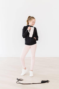 young girl wearing pale pink girls active leggings posing with a water bottle and jump rope