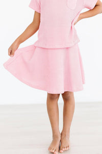 girl wearing girls bubblegum pink twirl skort holding hem while standing barefoot
