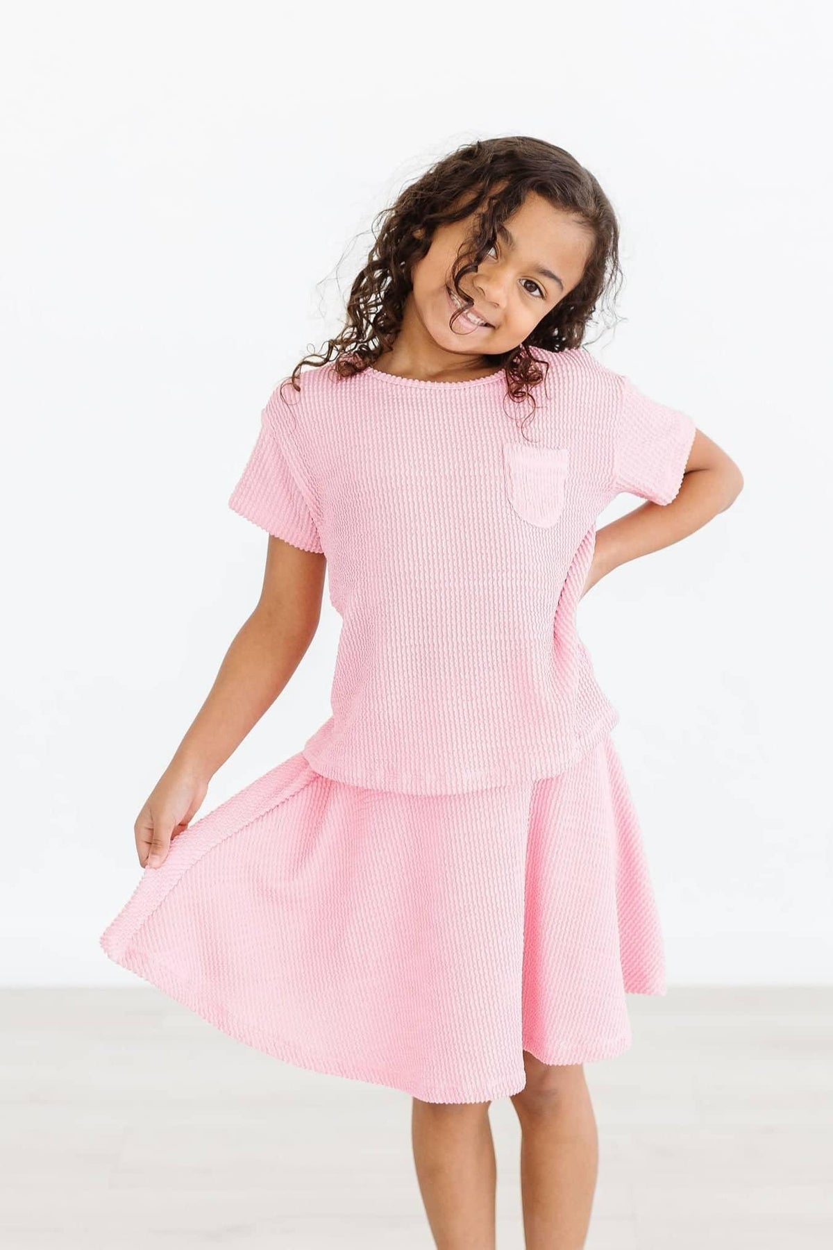 girl wearing girls bubblegum pink twirl skort smiling and holding skirt edge