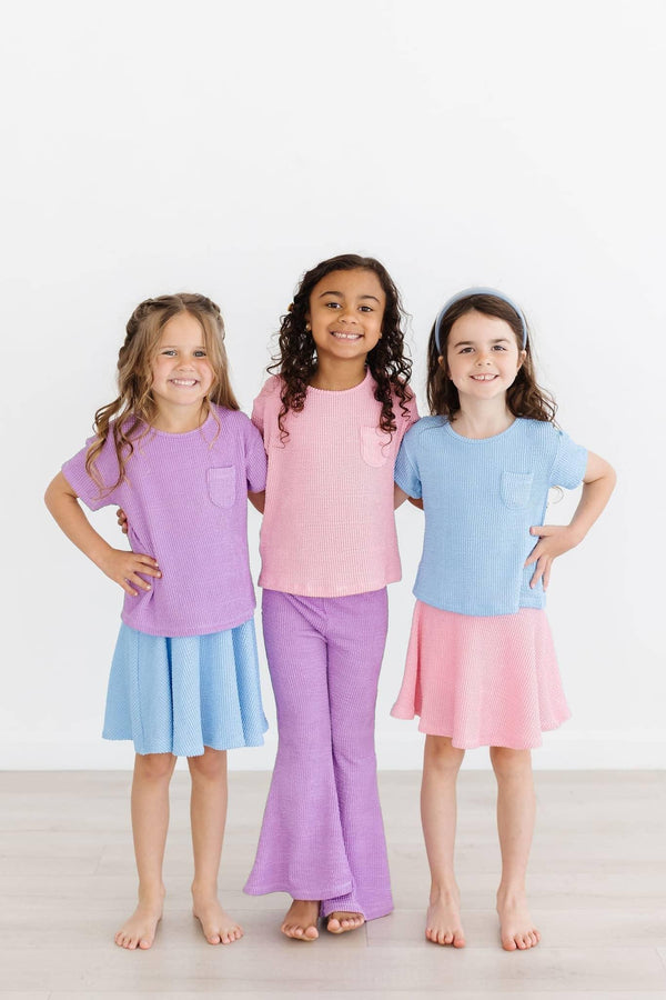 Girl wearing girls bubblegum pink twirl skort smiling with two friends in colorful outfits