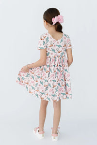 Young girl wearing pink girls cactus twirl dress holding hem and standing with back to camera