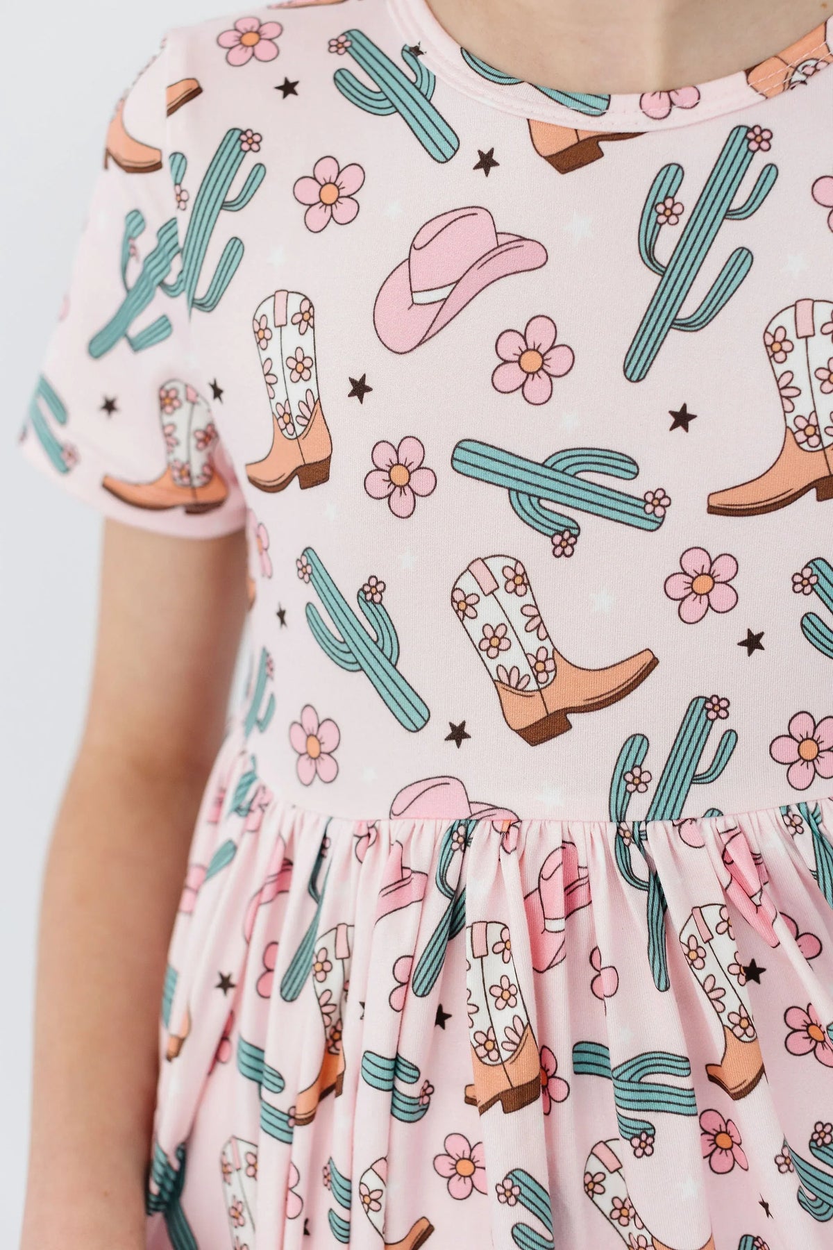 Close-up of girl wearing pink girls cactus twirl dress with cowboy boots and cactus pattern