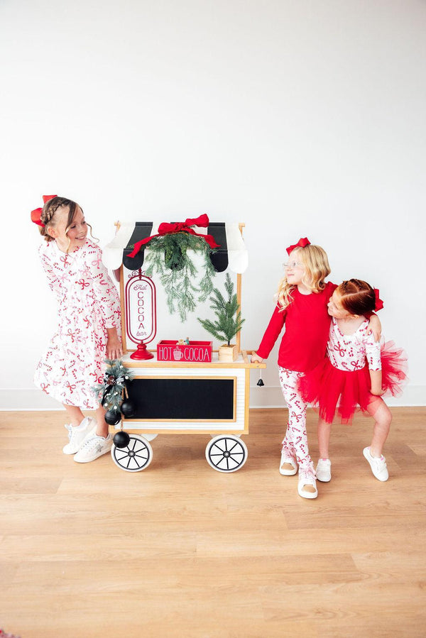 Girls candy cane leggings in white and red worn by kids with holiday-themed outfits
