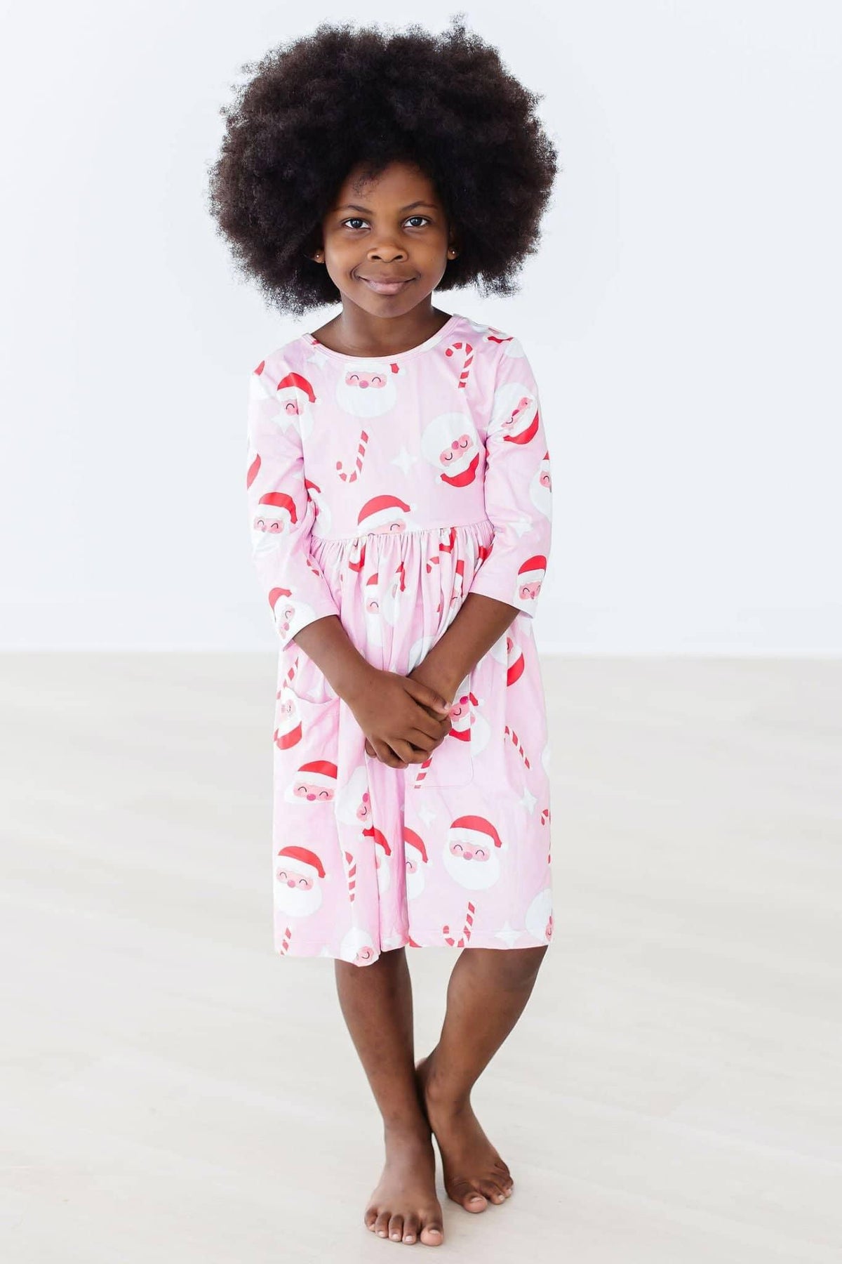 Girls pink Christmas twirl dress with Santa print, 3/4 sleeves, mid-length from Mila Rose