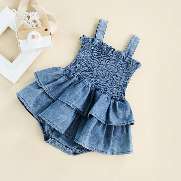 blue girls denim romper 0-24 months with ruffled tiered skirt and smocked bodice on beige background