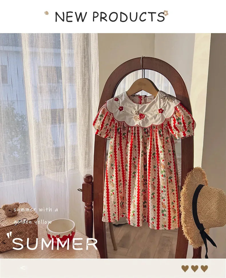 Girls embroidered strawberry dress in red and white cotton with floral collar hanging on wooden hanger