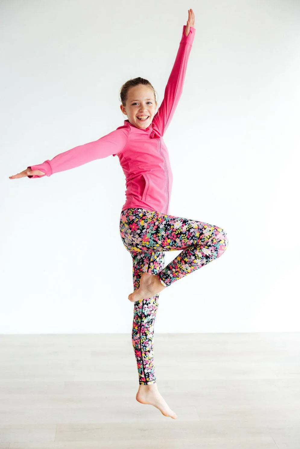 Girls floral leggings in colorful print worn by smiling young girl in pink long sleeve active top