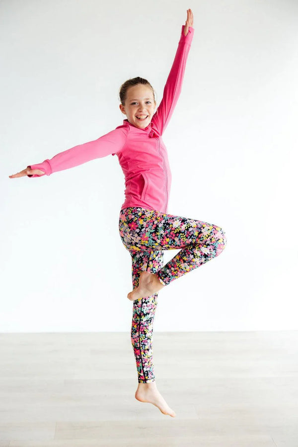 Girls floral leggings in colorful print worn by smiling young girl in pink long sleeve active top