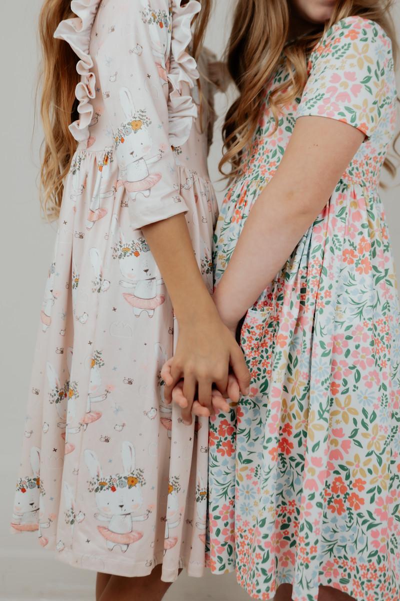 Two girls holding hands wearing pink and floral girls floral twirl dress standing side by side