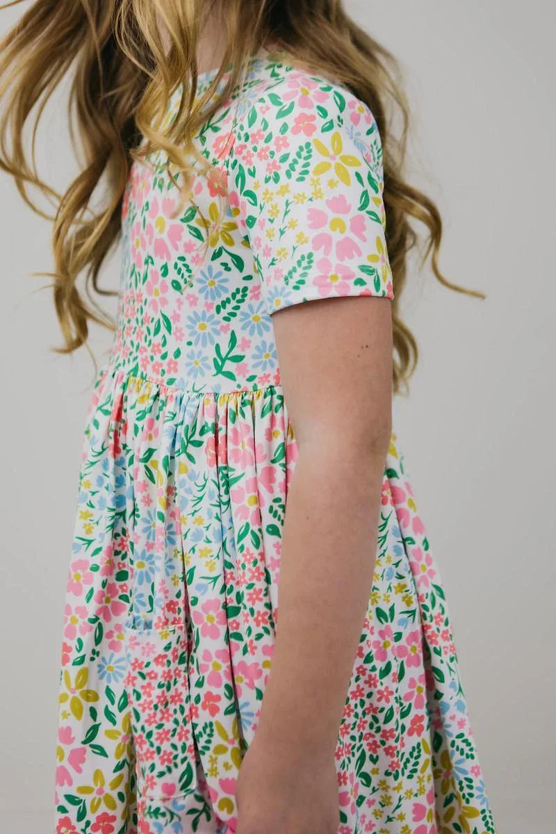 Girl wearing colorful girls floral twirl dress with short sleeves twirling side view