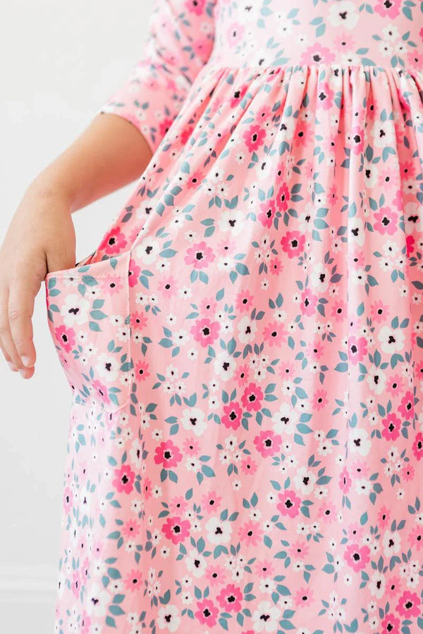 young girl wearing pink girls floral twirl dress with 3/4 sleeves showing pocket detail
