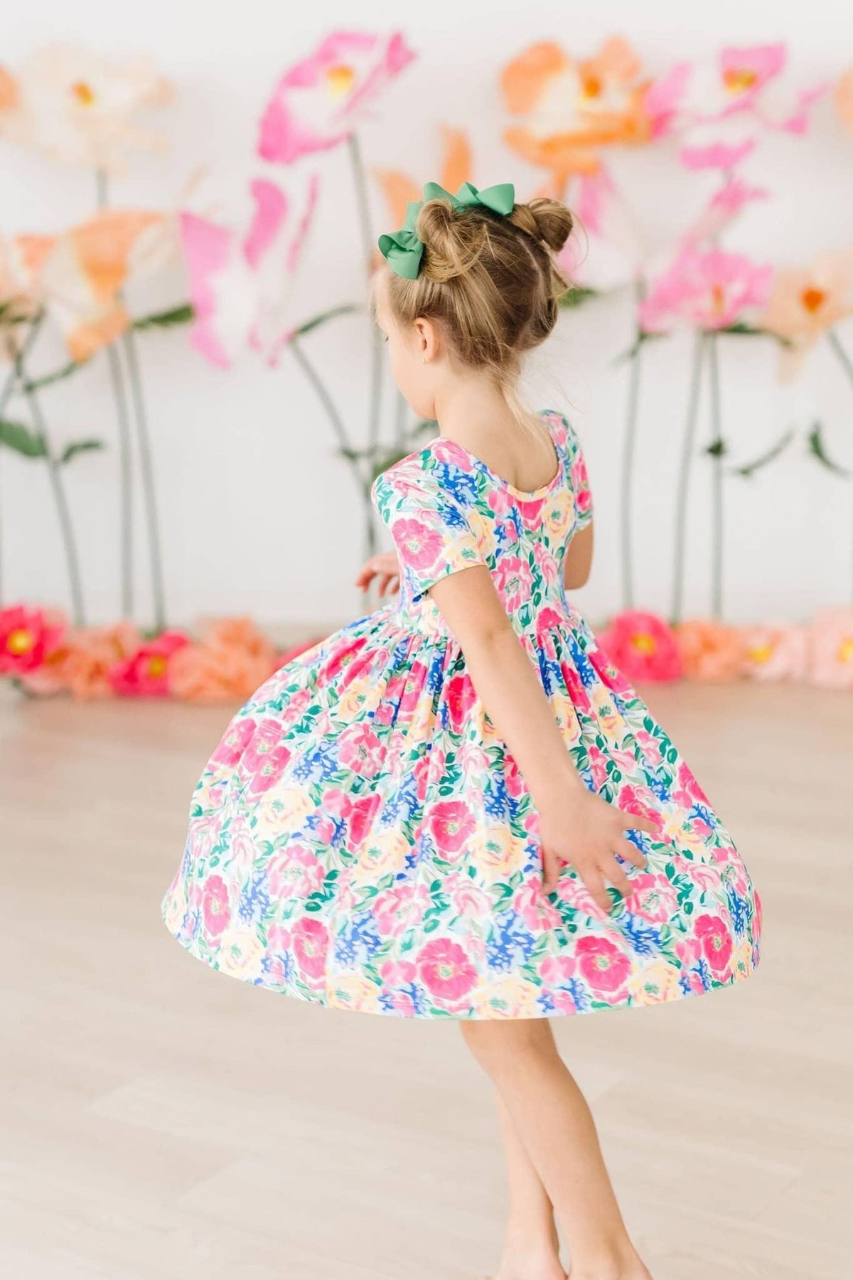 Young girl twirling in a colorful girls floral twirl dress with short sleeves and floral pattern