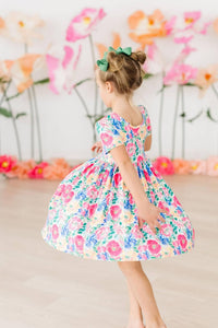 Young girl twirling in a colorful girls floral twirl dress with short sleeves and floral pattern