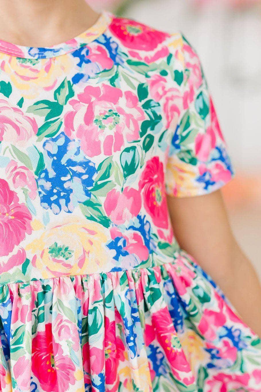 Toddler girl wearing colorful girls floral twirl dress with short sleeves holding skirt