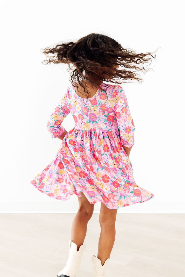 Young girl wearing pink girls floral twirl dress spinning with white boots in bright setting