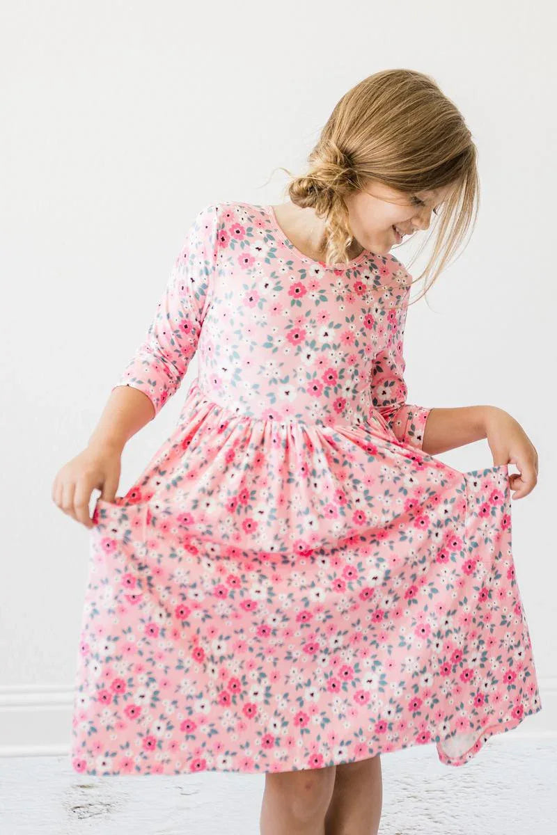 Young girl wearing pink Mila & Rose girls floral twirl dress holding the skirt while twirling
