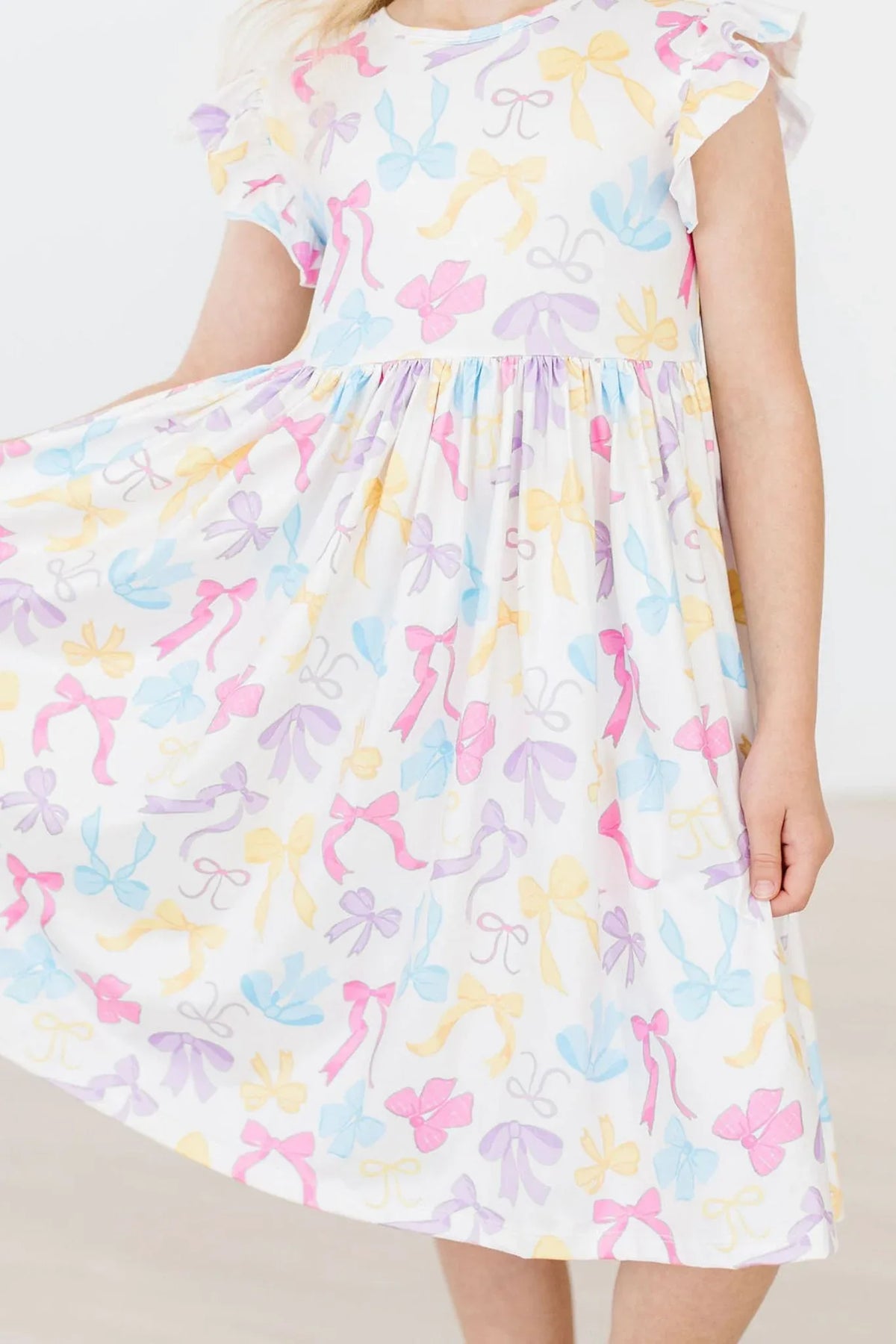 Girls flutter sleeve twirl dress in white with pastel bow print for young girls by Mila & Rose