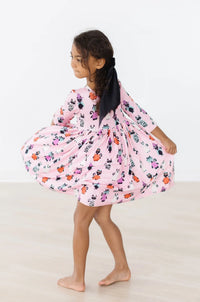 Young girl wearing pink girls Halloween twirl dress with pumpkins and bats twirling barefoot indoors