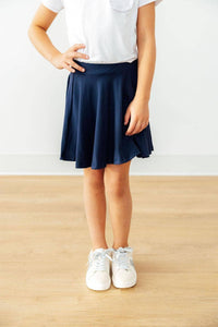 Girl wearing girls navy skort with shorts standing with hand on hip in white shirt and sneakers