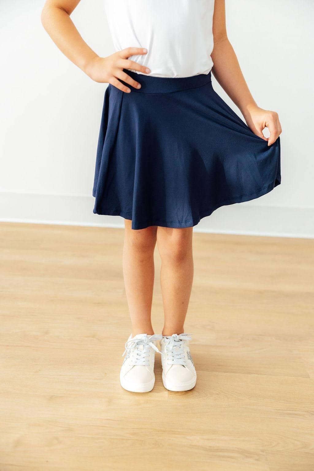 young girl wearing girls navy skort with shorts twirling while standing on wooden floor