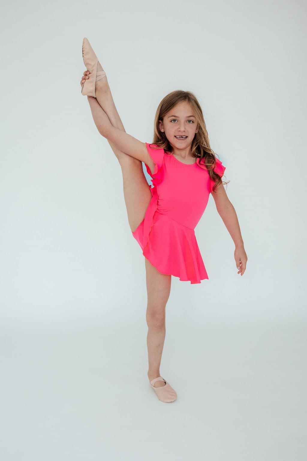 Girl wearing girls neon pink twirl leotard performing high leg stretch pose