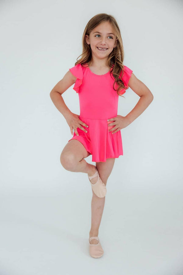 Girl wearing girls neon pink twirl leotard in a dancing pose with one leg raised