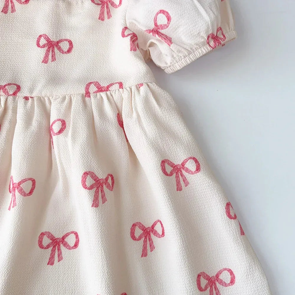 Cream textured girls pink party dress with pink bow patterns made of soft fabric for kids