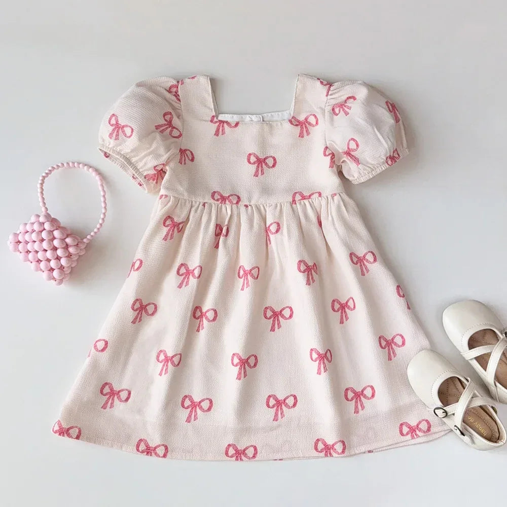 Girls pink party dress with puff sleeves made of soft cotton featuring pink bow prints