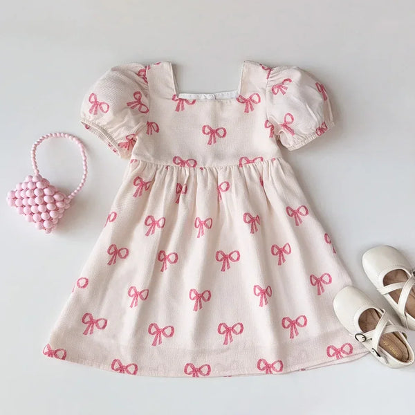 Girls pink party dress with puff sleeves made of soft cotton featuring pink bow prints