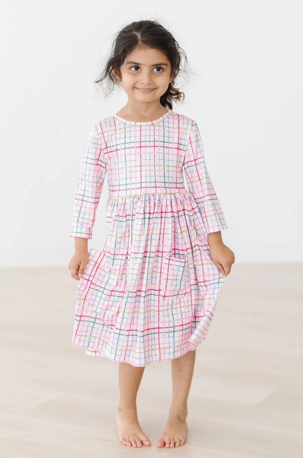Girls pink plaid twirl dress with 3/4 sleeves, knee-length, and colorful grid pattern